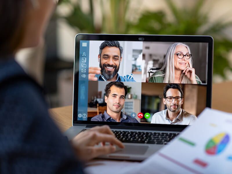 Video conference on a laptop with four participants in a grid layout