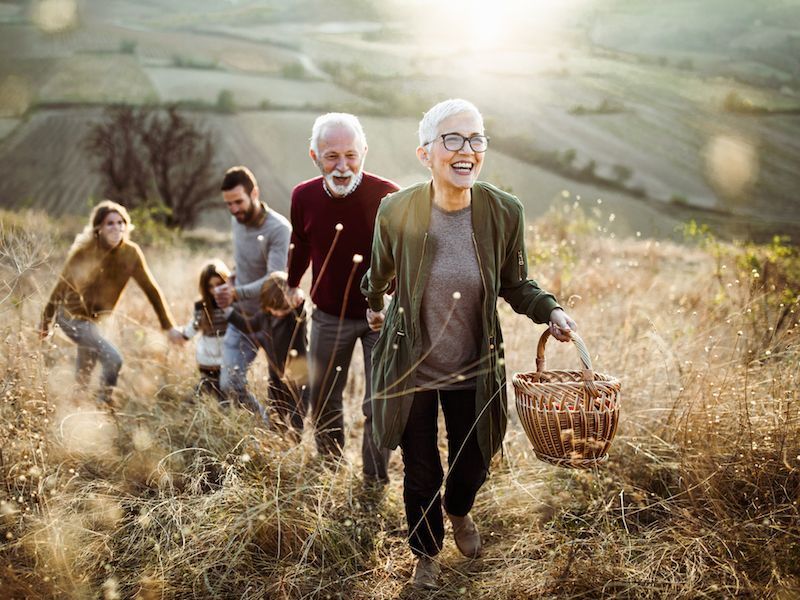 Group hiking through a grassy hillside at sunset, with one person carrying a basket in front.