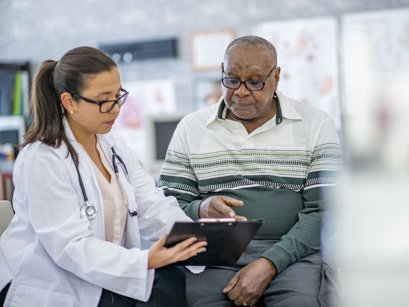 Clinician reviewing a tablet with an older patient in a medical office