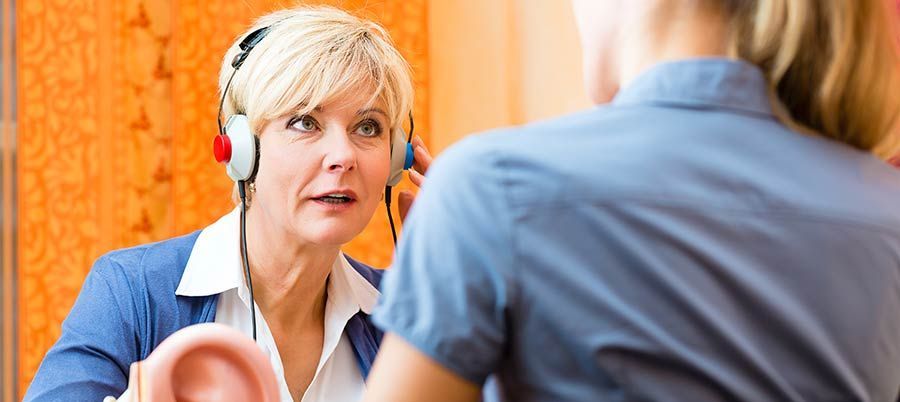 Woman wearing a headset speaking with a man in a blue shirt, indoors, close-up conversation