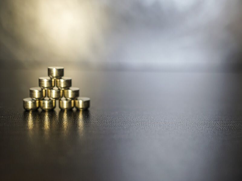 Stacked gold coins on a dark reflective surface, with a blurred background