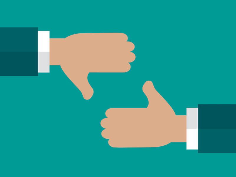 Two hands in sleeves showing thumbs down on a teal background