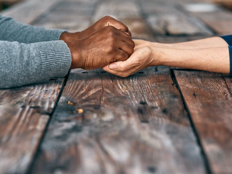 Two hands clasped in a handshake over a wooden table
