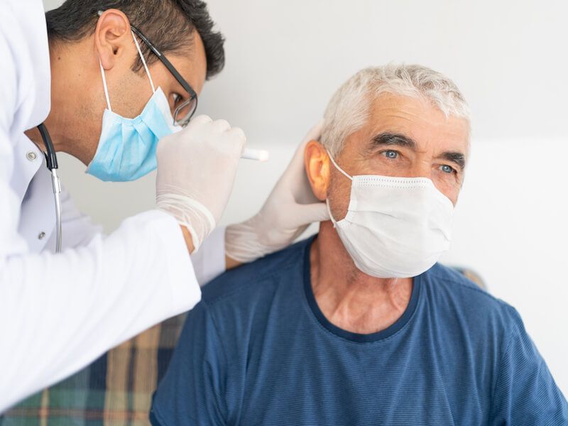 Dentist examining an older patient wearing a mask during a dental checkup