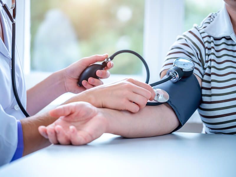 Doctor taking blood pressure with cuff on patient’s arm in a clinic
