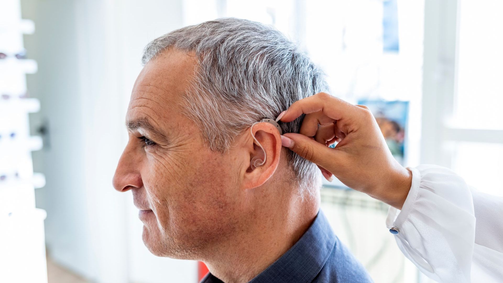 Person receiving an ear exam from a clinician in a bright clinic setting