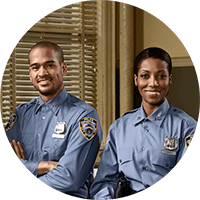 Two uniformed security officers standing side by side in an office setting, arms crossed, smiling
