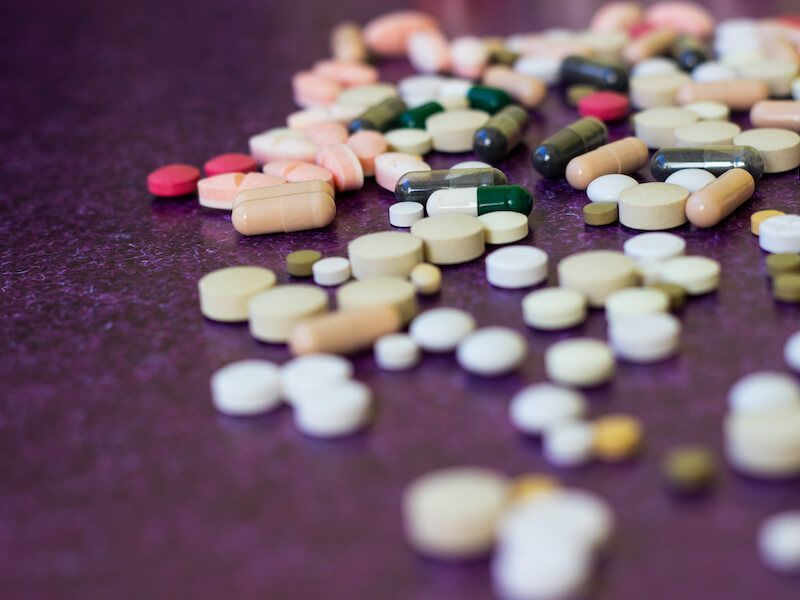 Scattered colorful pills and tablets on a dark surface
