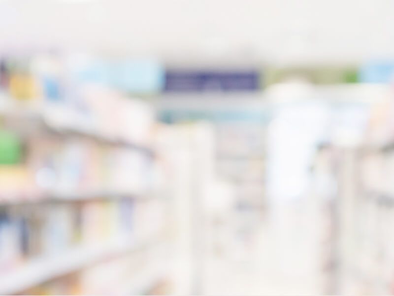 Blurred interior of a brightly lit grocery store aisle with shelves on both sides