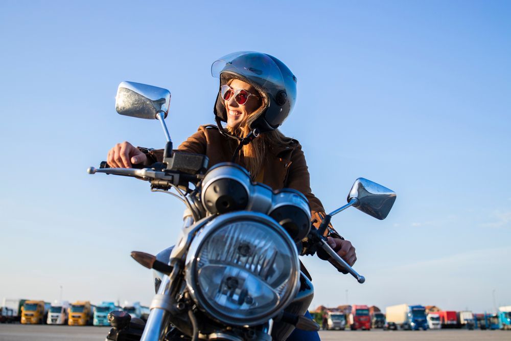 Motorcyclist in helmet and sunglasses on a chrome bike under a blue sky