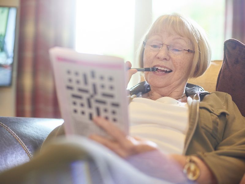 Woman smiling on a couch, reading from a tablet in a bright living room