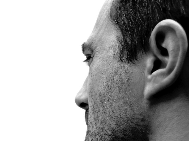 Black-and-white close-up side profile of a man's face and ear