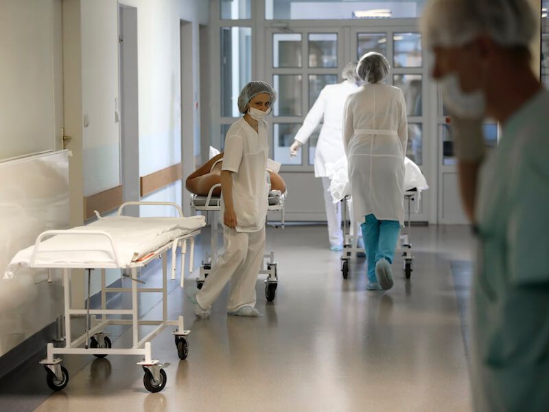 Hospital corridor with healthcare workers moving equipment and beds during a shift change