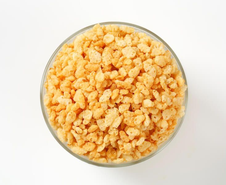 Top-down view of a glass bowl filled with orange, crunchy cereal pieces