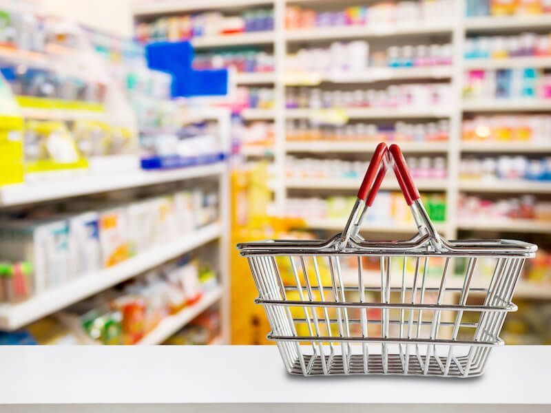 Shopping cart with red handle in a brightly lit supermarket aisle