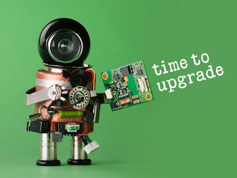 Toy robot on green background holding a circuit board, with text “time to upgrade”