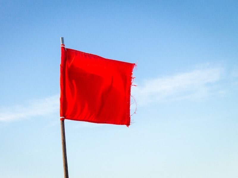Red flag on a pole against a clear blue sky.
