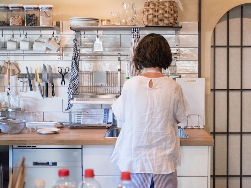 Person in a white shirt standing at a kitchen counter in a bright, organized kitchen