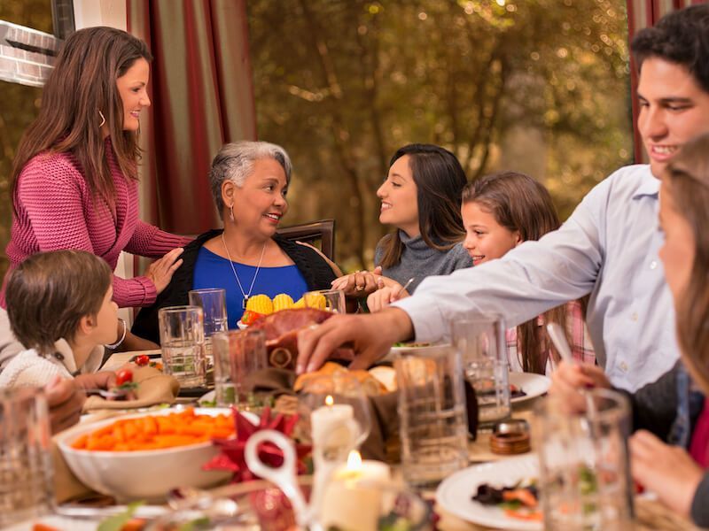 Family gathered around an outdoor table sharing a meal and conversation in a warm garden setting