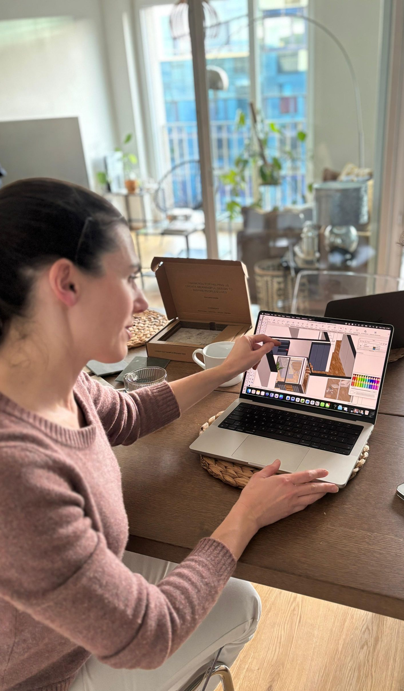 Une personne utilise un ordinateur portable sur le comptoir d'une cuisine, avec un appel vidéo ouvert à l'écran.