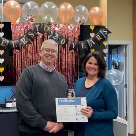 Two people holding a certificate at a 10 years celebration with balloons and festive decorations