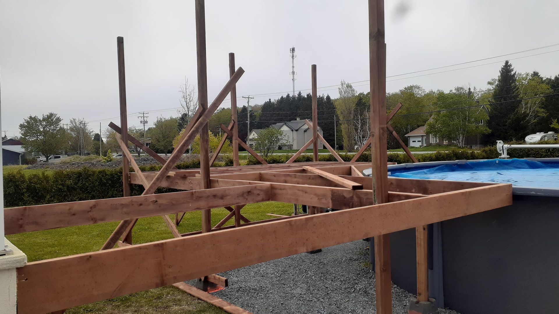 Une terrasse en bois est en cours de construction à côté d'une piscine.