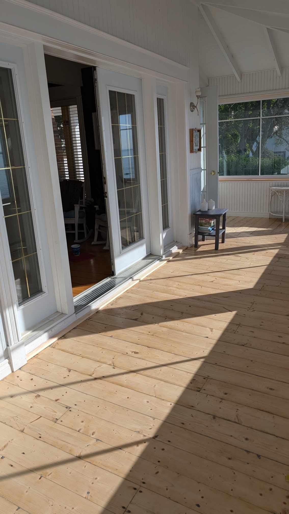 Une grande pièce avec parquet et portes coulissantes en verre.
