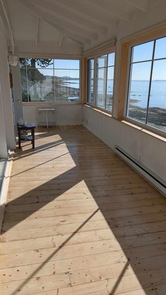 Une grande pièce avec parquet et beaucoup de fenêtres donnant sur l'océan.