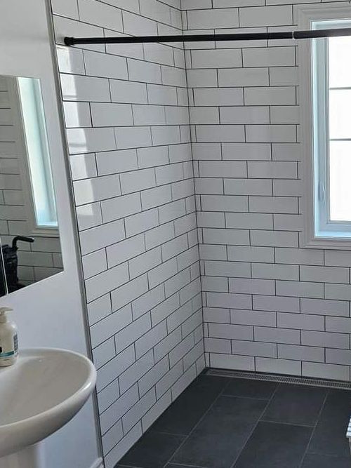 Une salle de bain avec des murs en briques blanches, un lavabo, un miroir et une douche à l'italienne.