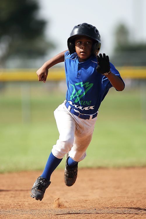 A baseball player in a blue uniform and helmet running across a dirt field during a game.