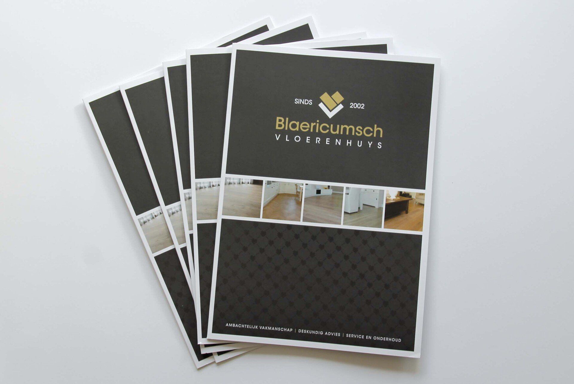 Een stapel identieke marketingbrochures met een zwart-wit ontwerp, interieurfoto's en een goudkleurig bedrijfslogo.