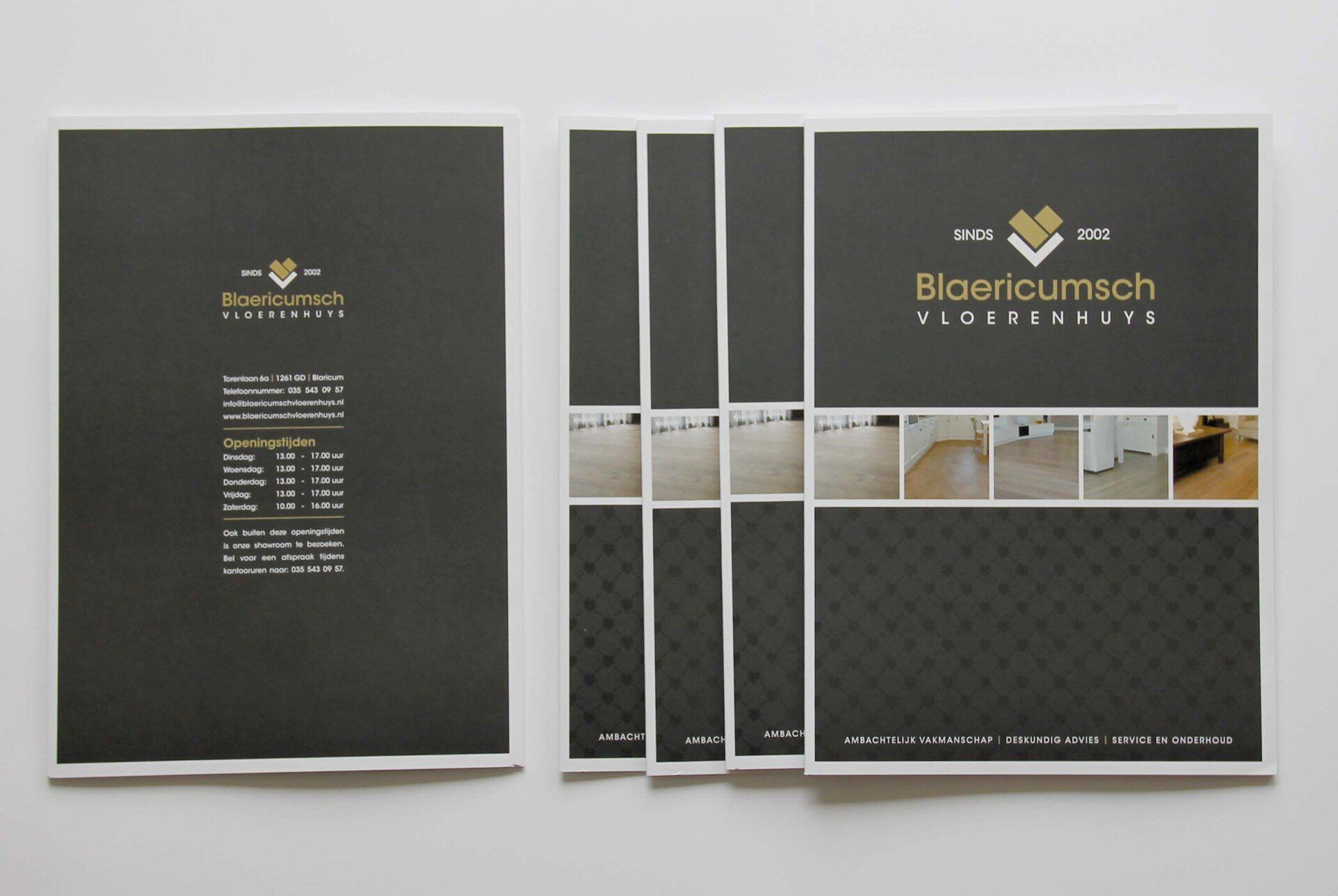 Een platte weergave van meerdere op elkaar gestapelde donkergrijze informatiebrochures met een goudkleurig bedrijfslogo, tekst en foto's van vloeren.