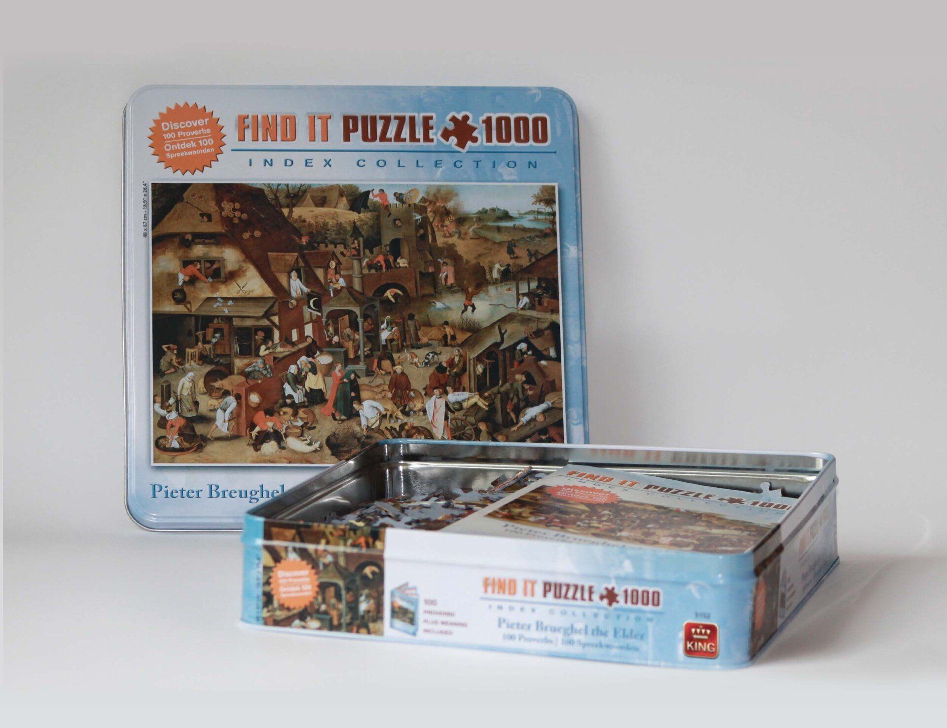 Een blikken puzzeldoos die rechtop staat, met daarvoor een tweede open blikken doos. Beide dozen zijn voorzien van een schilderij van Pieter Bruegel, gemaakt van blauwe blikken.