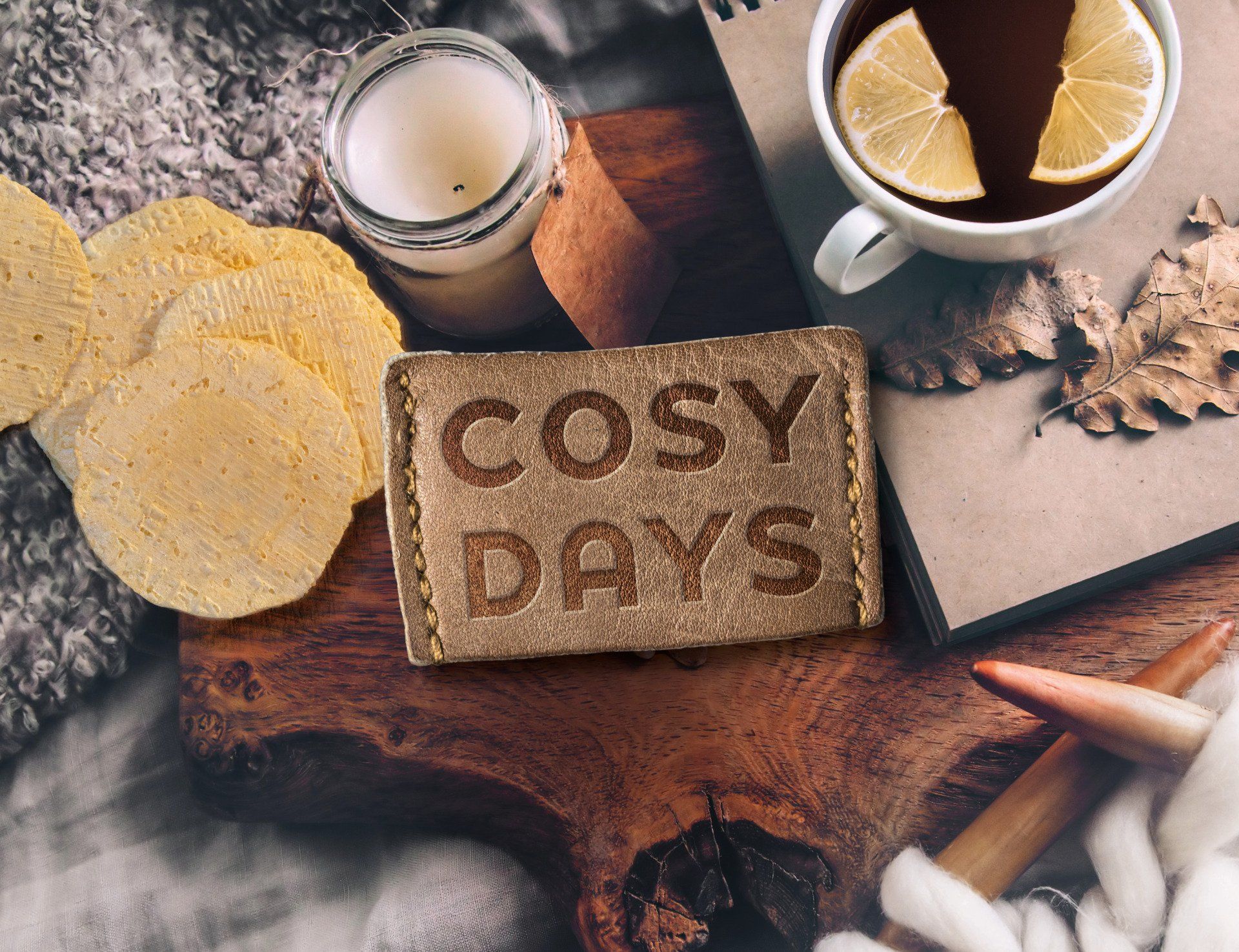 Een knusse flat lay met een kaars, een mok thee met citroen, snacks en een label met de tekst 