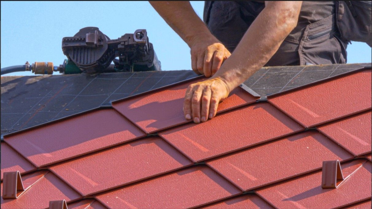 A man is working on a roof with red tiles.