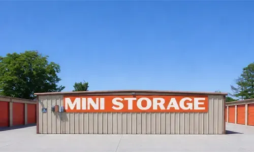 Mini storage facility with beige and red units under a clear blue sky