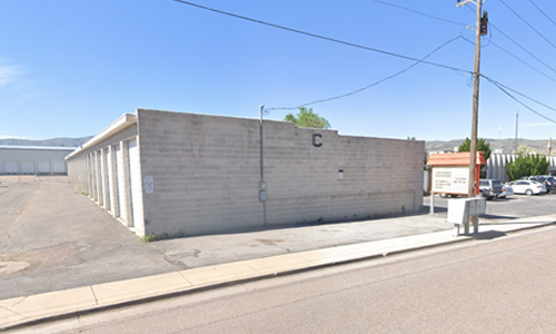 Concrete industrial building beside a street under a clear blue sky, with utility poles and a sidewalk sign.