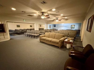 Spacious living room with blue carpet, leather sofas, columns, and a ceiling light fixture