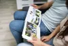 Two people on a couch look at a photo album with outdoor pictures.