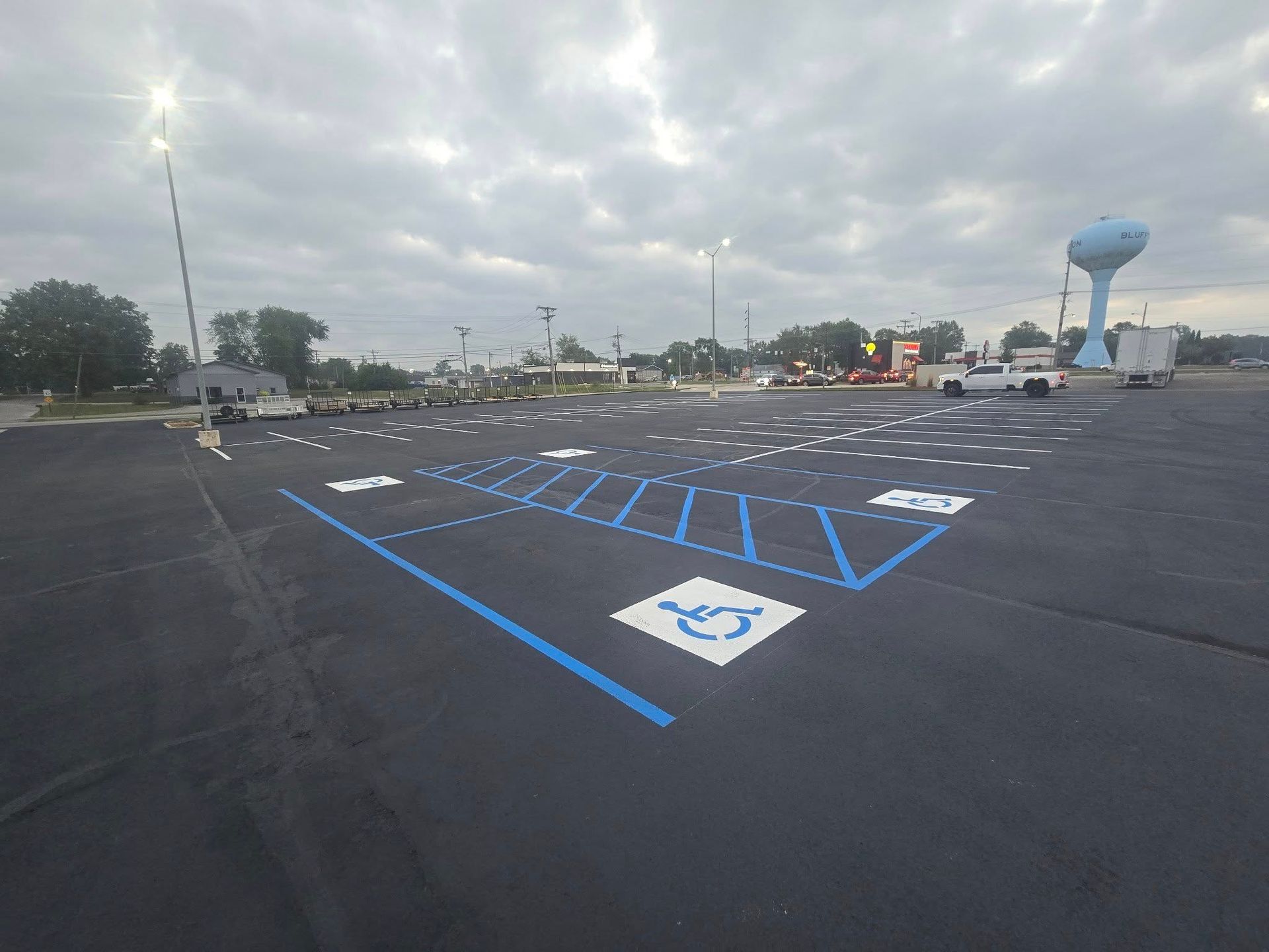 Empty parking lot with blue accessible parking markings and a blue water tower in the distance