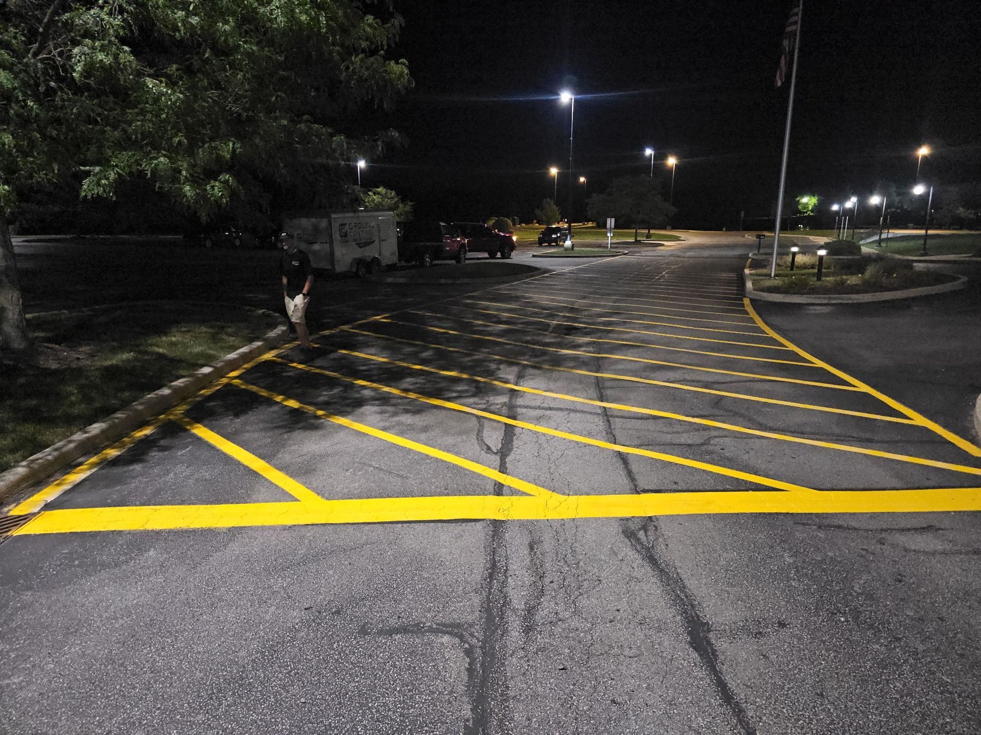 Empty parking lot at night with yellow painted no-parking markings and streetlights
