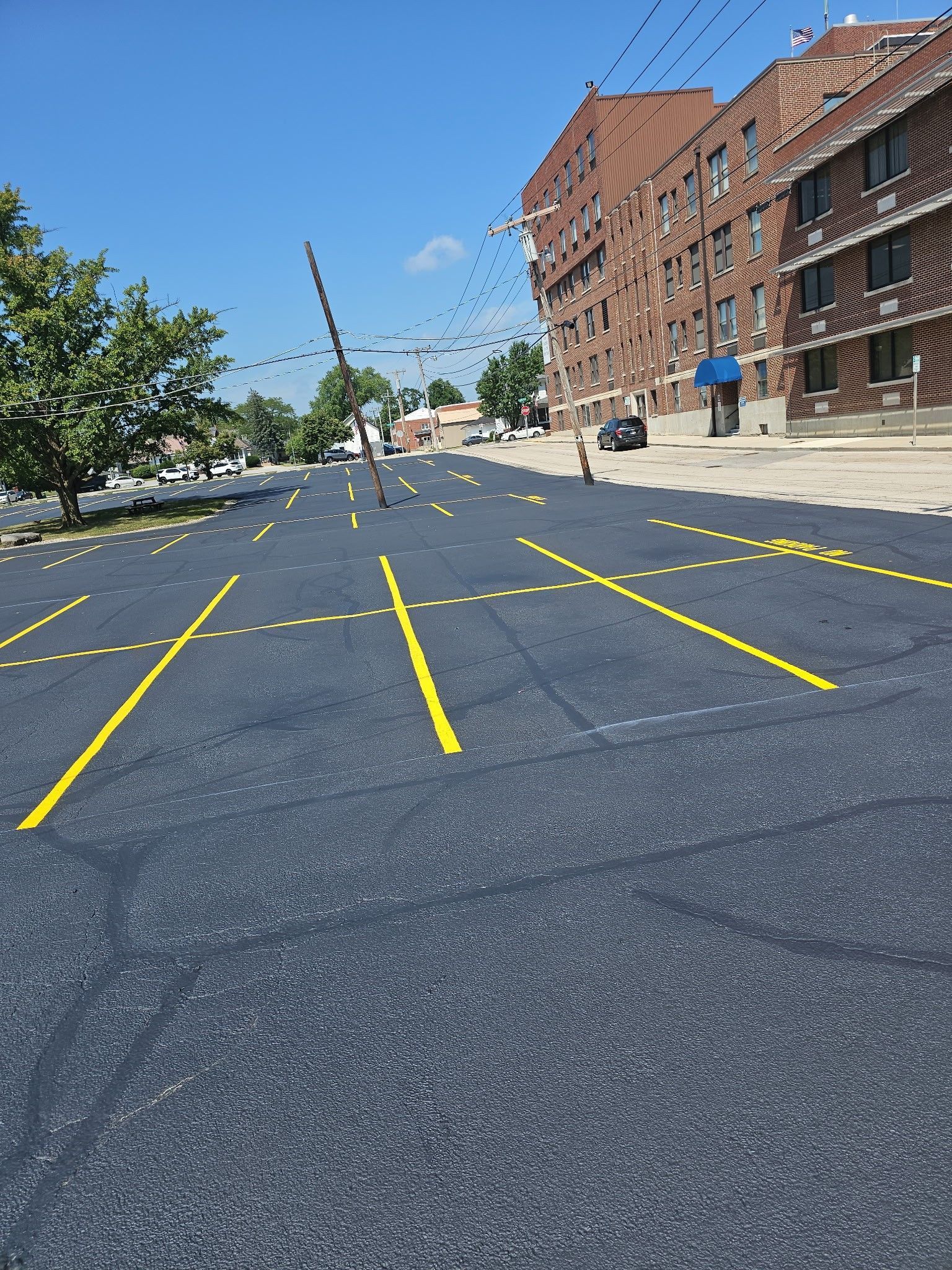 Empty city street with yellow lane markings beside a brick building on a sunny day