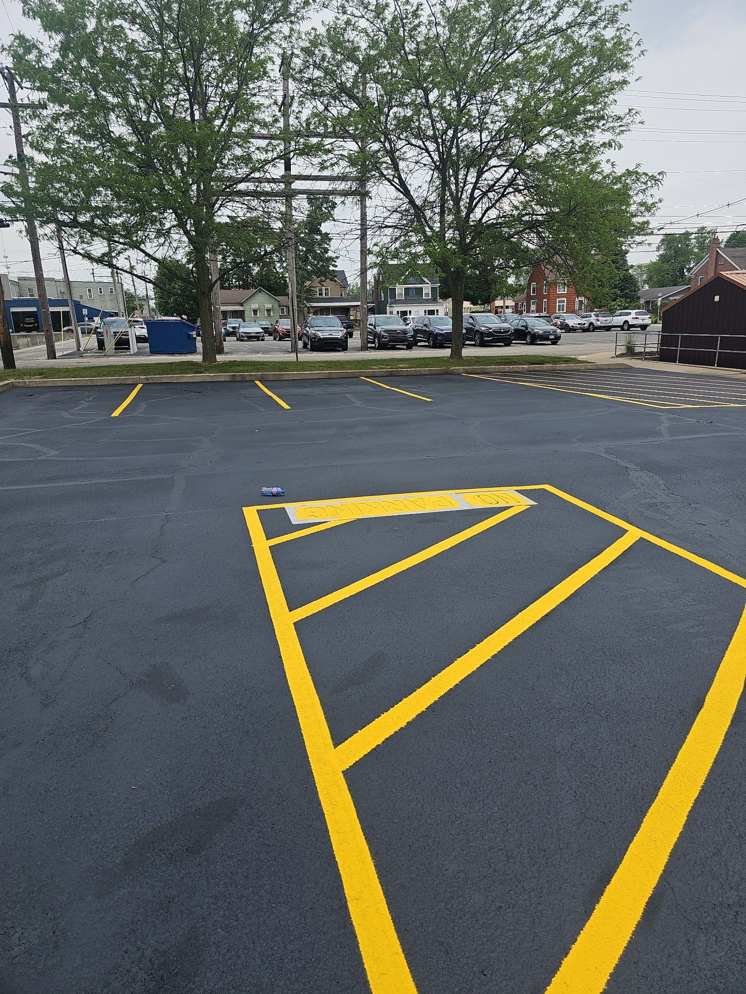 Empty parking lot with yellow hatch markings and trees in the background