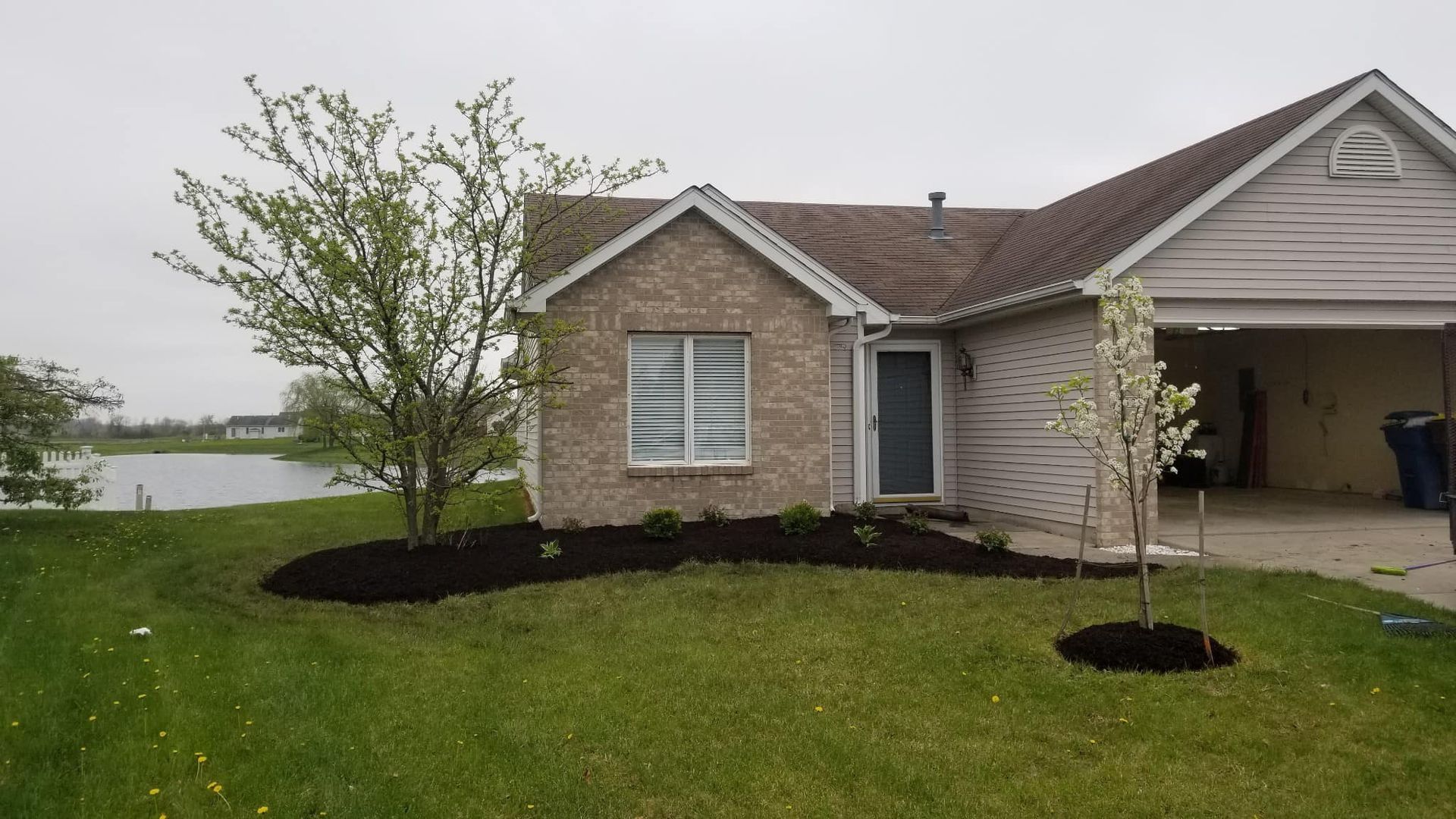 Suburban house with new landscaping, a green lawn, and a lake in the background