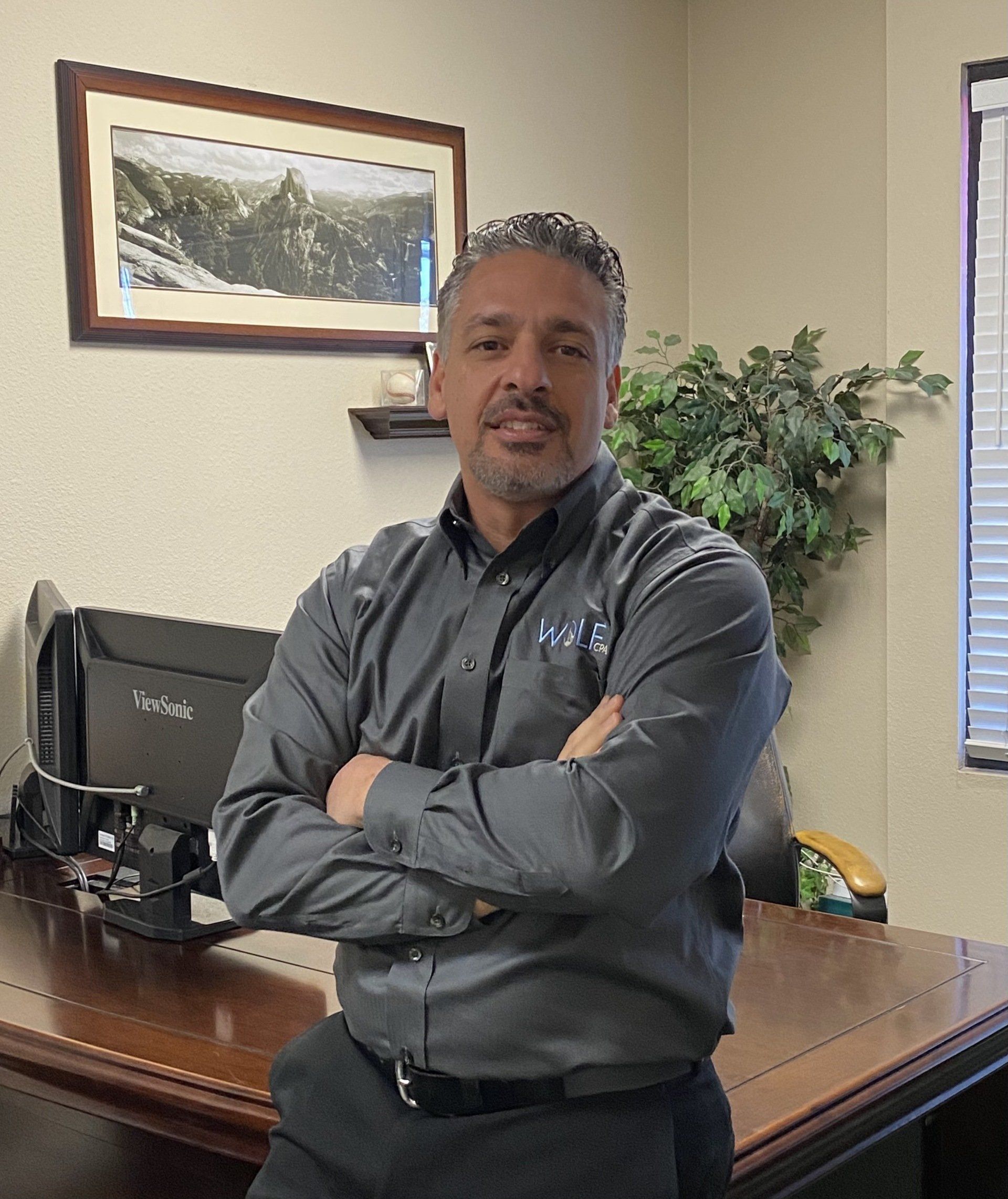 Chris Wolf standing in front of a desk with his arms crossed.