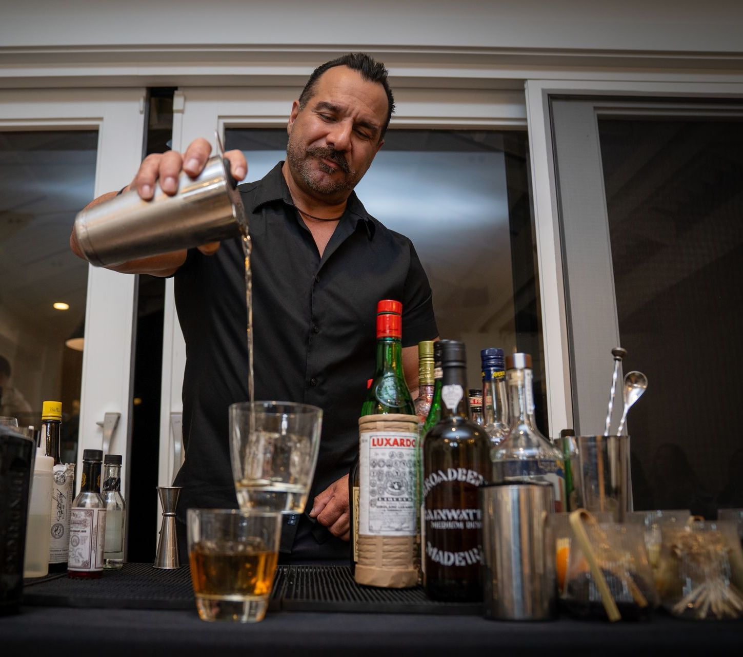 A bartender is pouring a drink into a glass