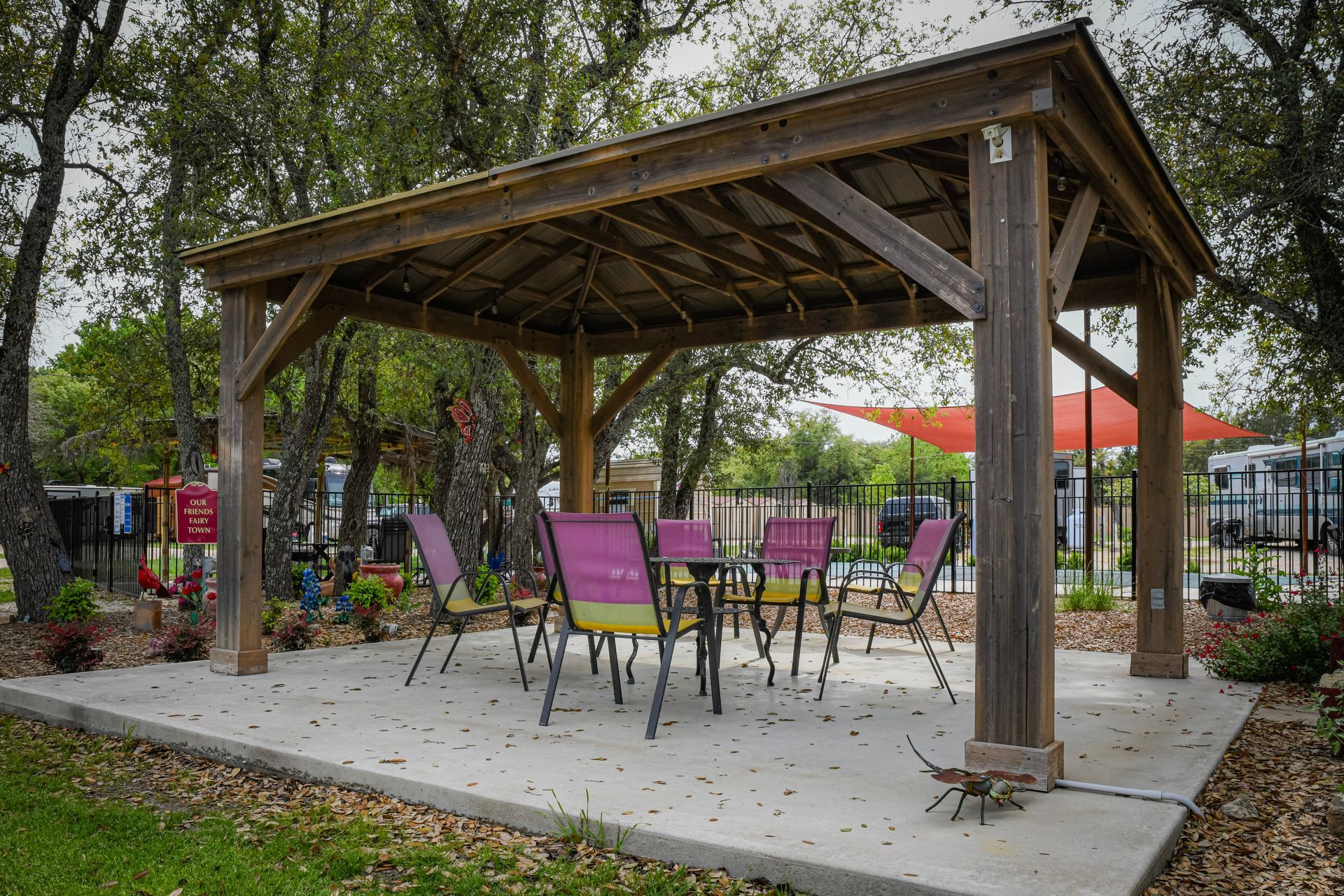 A wooden gazebo with a table and chairs underneath it.
