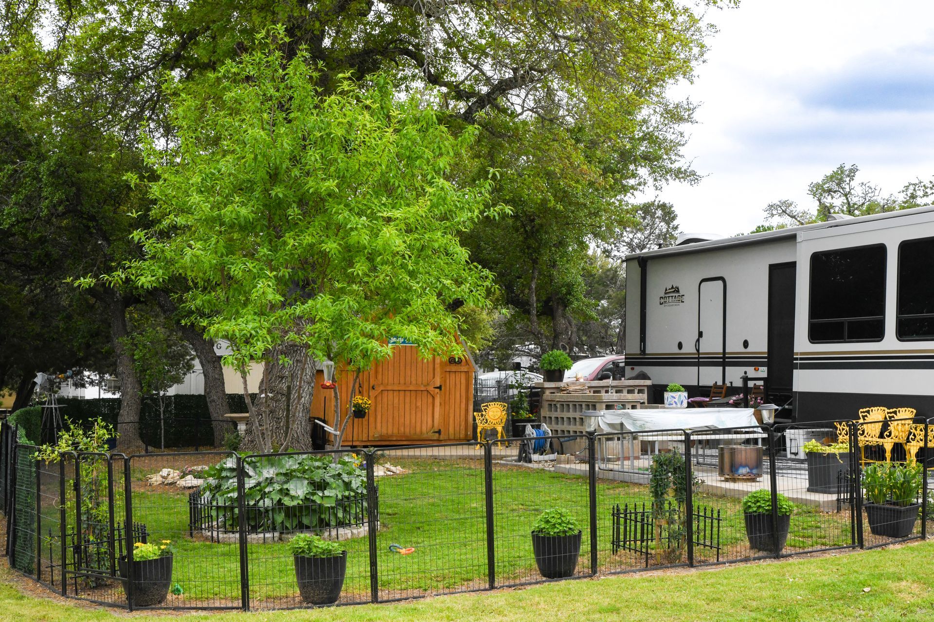 A fenced in yard with a rv parked in the background.