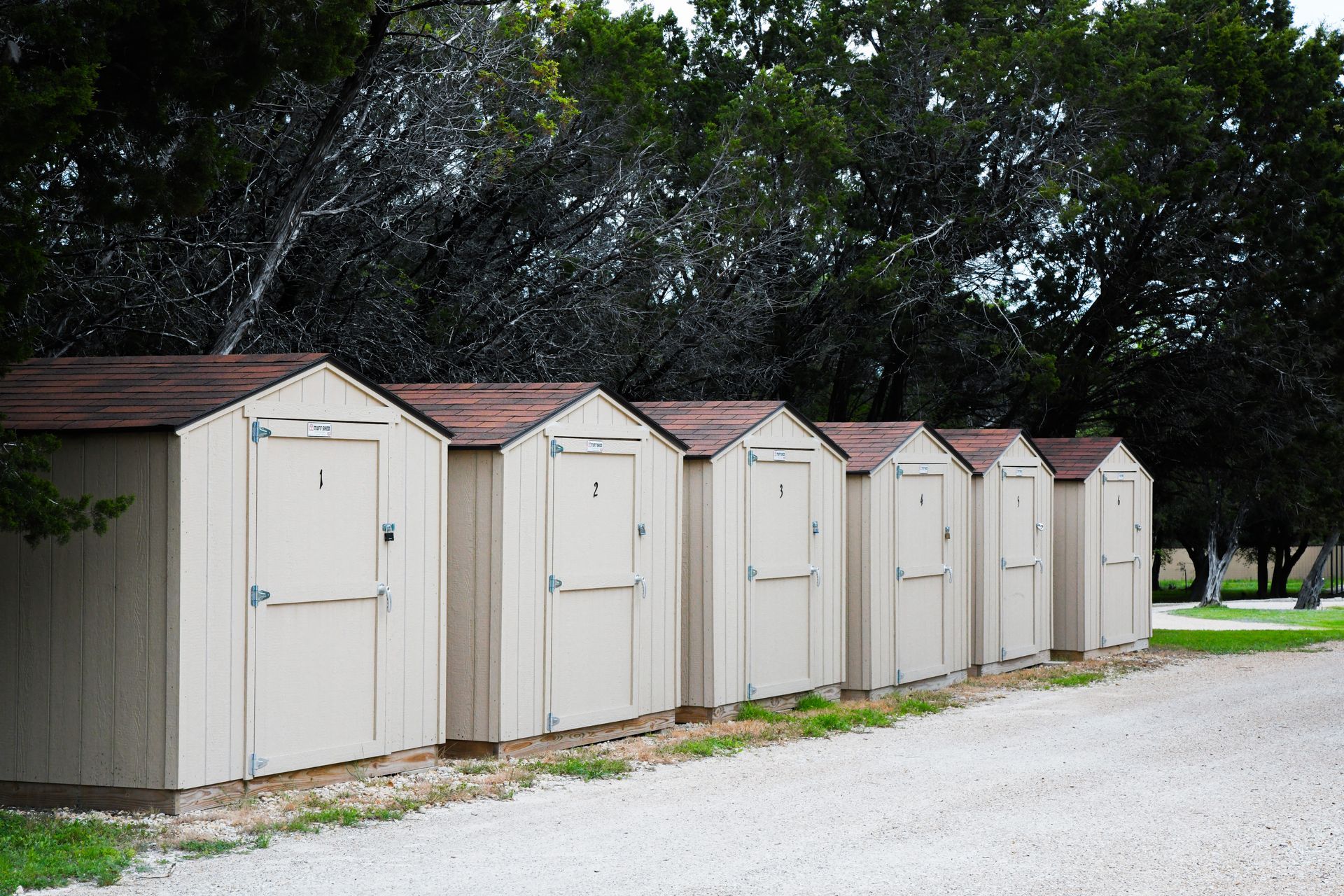 A row of sheds are lined up on a gravel road