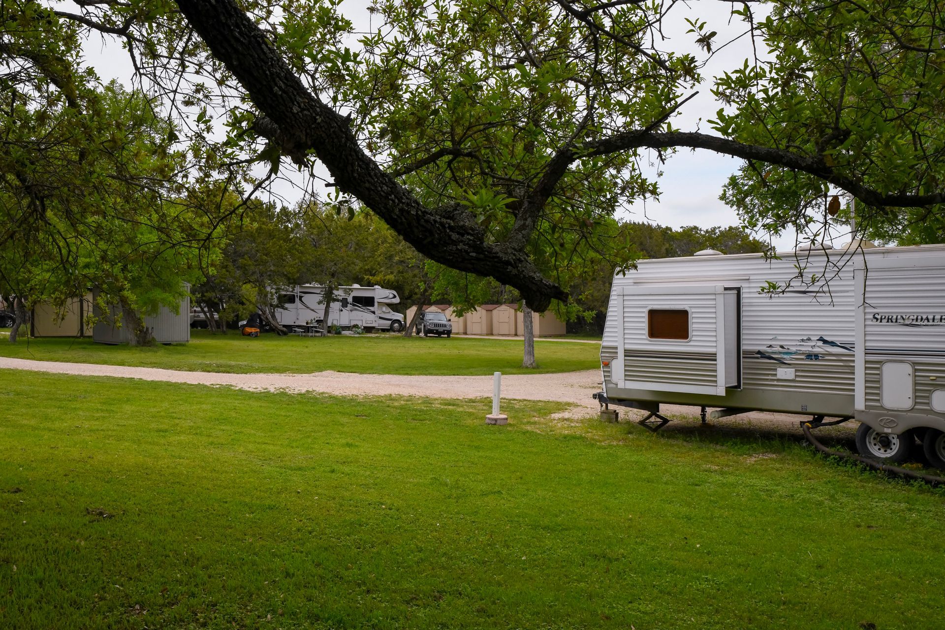 A trailer is parked in a grassy field next to a tree.